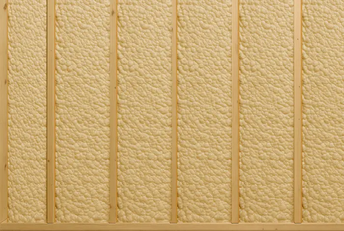 Wall cavities completely filled with spray foam insulation between wooden studs.